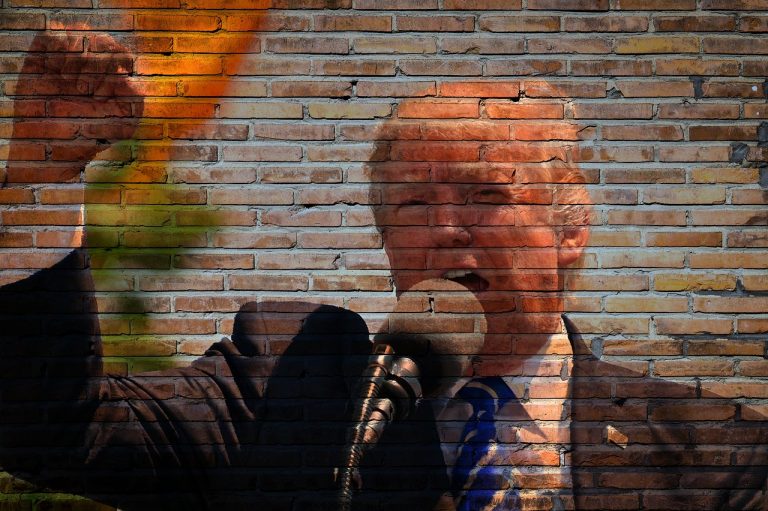 Street art portrait of a man on a brick wall, appearing to be a mural