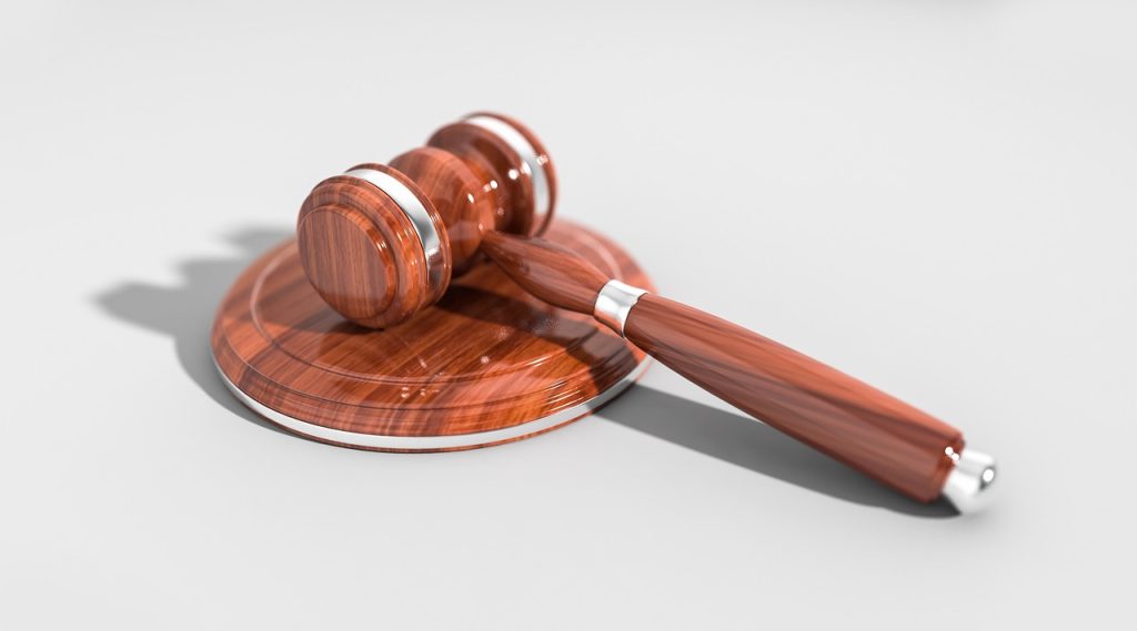 A wooden judge’s gavel rests on its sound block