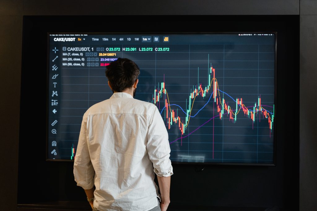 Back view of a trader analyzing cryptocurrency data on a monitor indoors