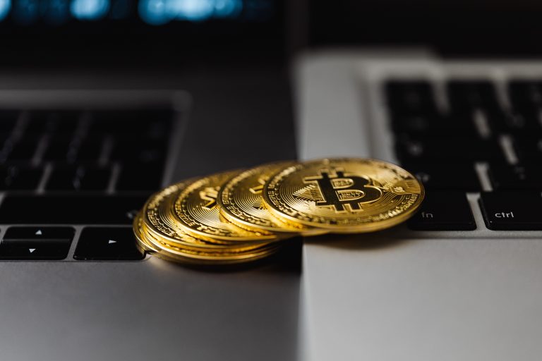 Close-up of gold Bitcoin coins placed on laptop keyboards, representing digital currency and wealth